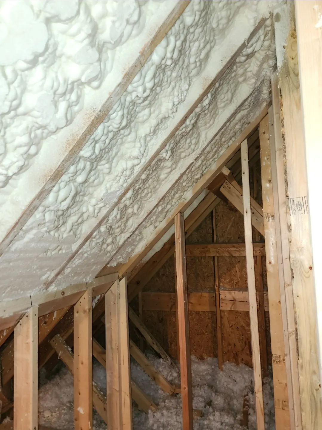 Spray foam insulation applied between the rafters of an attic roof deck